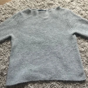 Grå ribbad stickad tröja från MNG - Säljer en grå stickad tröja från MNG i storlek S. Tröjan har ett ribbat mönster, rund hals och långa ärmar. Perfekt för dig som gillar enkel och stilren design med mjukt material som håller dig varm under kyliga dagar.