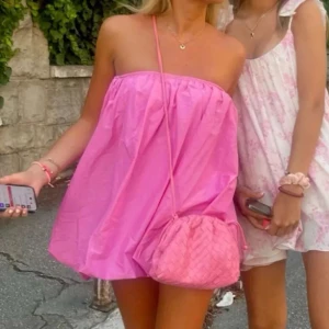 Rosa kortklänning - Supersöt rosa kortklänning med axelbandslös design och luftig passform. Perfekt för varma dagar och ger en riktigt fräsch vibe. Klänningen har en enkel, stilren look och är lätt att matcha med accessoarer.