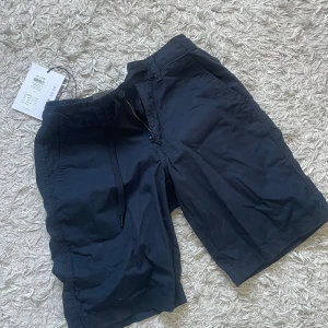 Svarta shorts från Only & Sons - Snygga svarta shorts från Only & Sons med klassisk passform, storlek S. Nya med prislapp kvar. De har snörning i midjan, dragkedja och knapp framtill samt sidfickor. Säljer ett par exakt likadana i beige!