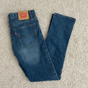 Levi's 511 blå jeans - Säljer ett par klassiska Levi's 511 jeans i blå denim. Modellen har en slim passform med raka ben och normal midja. Jeansen har fem fickor, Levi's ikoniska läderpatch bak och röda logotag på bakfickan. Perfekta till sneakers eller boots.