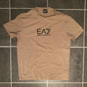 Beige EA7 Emporio Armani t-shirt - Snygg beige t-shirt från EA7 Emporio Armani i storlek L.                                                            (Liten i storleken passar bättre på än med M)