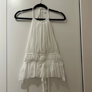 Topp - Supersöt vit topp med volangkant och knyt i nacken och ryggen. 