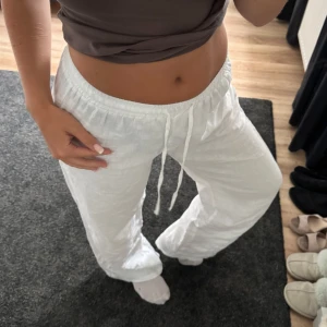 Vita linnebyxor med snörning - Säljer ett par fräscha vita linnebyxor med elastisk midja och snörning. Byxorna har en avslappnad passform och raka ben, perfekta för varma dagar. Lätta och luftiga i materialet, riktigt sköna att bära. Satt en egen smal söm på insida lår