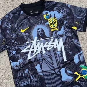Brasil x Stüssy jearsy   - Unik svart fotbollströja från Nike i samarbete med Stüssy och Brasil. Tröjan har coolt grafiskt tryck med Kristusstatyn, brasilianska flaggan och CBF-emblem i gult. Kortärmad modell med Stüssy-logga över bröstet. Materialet är lätt och andas, perfekt för match eller streetstyle.