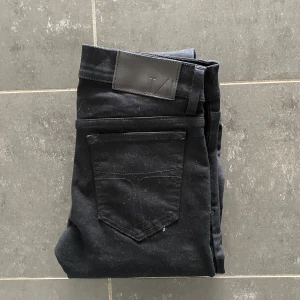 Tiger Of Sweden Jeans - Svarta jeans från Tiger Of Sweden i slim fit-modell, tillverkade i Sverige . Klassisk femficksdesign, raka sömmar och diskret svart patch bak i midjan. Snygga och stilrena jeans som passar perfekt till sneakers eller boots.