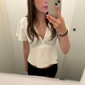 Vit T-shirt  - Vit T-shirt från Gina med band på sidorna som man kan knyta vid ryggen. Jag har sytt längst ner vid v ringningen för mer täckning men det går att spreta upp. Använd fåtal gånger. Pris går att diskuteras