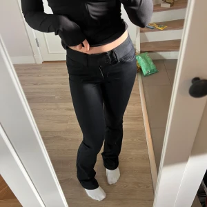 Svarta bootcut byxor med låg midja - Säljer ett par svarta byxor med bootcut-snitt och låg midja. Byxorna har två knappar i midjan och sitter tight upptill med utsvängda ben. Väldigt bra skick