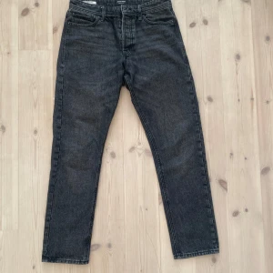 Svarta  jeans Jack & Jones - Säljer ett par svarta jeans från Jack & Jones i modellen Loose/Chris. Jeansen har loose fit, klassisk femficksdesign och raka ben. Materialet är denim och färgen är tvättad svart med lite slitningseffekt. Perfekta för en avslappnad stil.