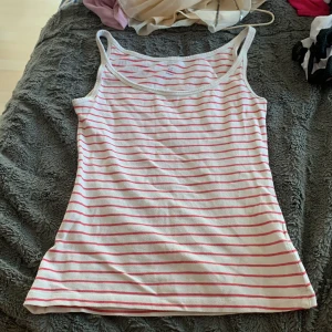 Randig linnetopp från H&M XS - Säljer en vit och rosa randig linnetopp från H&M i storlek XS. Toppen har smala axelband och är tillverkad i mjuk bomull, perfekt för varma dagar. Enkel och stilren design som är lätt att matcha med jeans eller shorts.