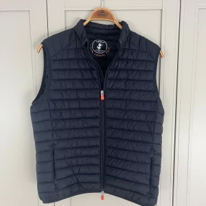 Save The Duck väst - Säljer en mörkblå, quiltad dunväst från Save The Duck. Storlek L sitter mer som M. Använd ett fåtal gånger, skick 9/10. Nypris: 1800kr