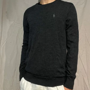 100% merinoullströja Polo Ralph Lauren - Svart långärmad tröja från Polo Ralph Lauren i tvättbar merinoull. Slim fit-modell med diskret broderad logga på bröstet. Perfekt för dig som gillar stilren och klassisk look med en modern touch.