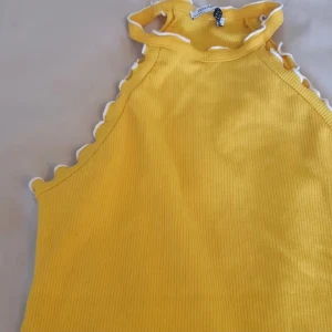 Gul ribbad linnetopp från Zara - Superfin gul ribbad linnetopp från Zara Trafaluc med vita vågiga kanter längs halsringning och ärmhål. Hög hals och ärmlös modell, perfekt för soliga dagar. 🌟 Eventuellt en liten liten fläck under ena armhålan, som säkert går bort med lite fläckborttagning (se nära på bild 2)