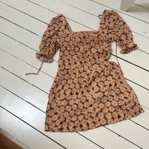 Kort sommarklänning med blommor - Super söt kort sommarklänning med blomm mönster och puffärmar, den har knyt k nacken och resår på ryggen