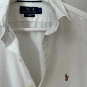 Vit Ralph Lauren Skjorta - Strl S, Slim Fit - Hej säljer nu min fina Ralph Lauren skjorta i storlek S och den sjukt populära modellen Slim Fit. Den är i nyskick och kommer vara otroligt snygg på sommaren. Nypris cirka 1600kr! Vid frågor eller fundering tveka inte på att höra av dig! 🌊🍾