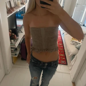 Beige tubtopp - Säljer en beige bandeau tubtopp från Zara med volangkant nedtill.  Perfekt för dig som gillar en trendig och avslappnad stil. Skriv om ni har några frågor🥰 