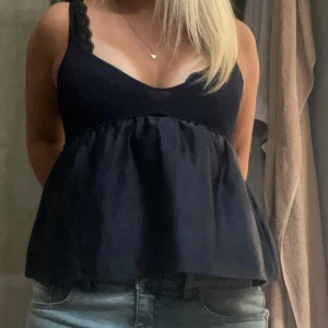 Mörkblå fest topp - Supersöt mörkblå fest topp som du lätt kan klä upp eller ner. Toppen har ribbat tyg upptill och ett flowy, utställd nederdel som ger en luftig känsla. Perfekt till jeans eller kjol för en chill look.