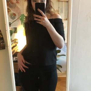 Svart offshoulder topp från Monki - Säljer en stilren svart offshoulder topp från Monki. Perfekt för en trendig look med sin axelbandslösa design. Toppen har en normal passform och är tillverkad i ett mjukt material. Tröjan har tyvärr ett hål på sidan men hade varit lätt att fixa!