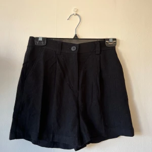 Svarta shorts från ASOS DESIGN - Snygga svarta shorts från ASOS DESIGN med hög midja och knappdetalj fram.