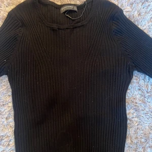 Svart ribbad tröja från Stradivarius  - Säljer en stilren svart ribbad tröja med rund hals. Perfekt för en enkel och elegant look. Tröjan har långa ärmar och är gjord i ett mjukt material som känns skönt mot huden.