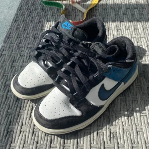 Nike Dunk i svart, vit och blå - Snygga Nike Dunk sneakers i en klassisk färgkombination av svart, vit och blå. Skorna passar både till flickor och pojkar! Perfekta för barn med stil!