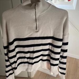 Randig ribbad tröja med dragkedja - Snygg ribbad tröja i vitt med svarta ränder och en dragkedja.