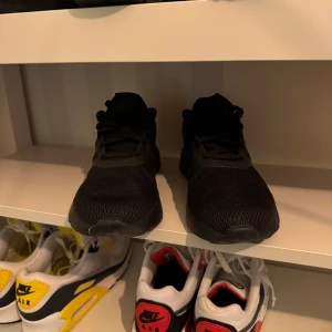 Svarta sneakers från Adidas - Säljer ett par svarta sneakers från Adidas. Skorna har en stilren design med snörning och är tillverkade i syntetmaterial. Perfekta för vardagsbruk och träning.