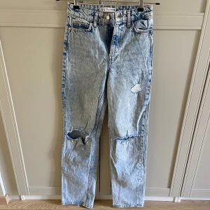Blå jeans från Zara - Säljer ett par blå jeans från Zara med slitna detaljer. De är högmidjade och raka i passformen. Slitningarna är lite slitna då trådarna gått av. Utöver det fint skick!💕
