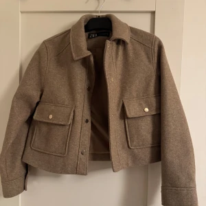 Beige jacka från Zara - Snygg brun/beige jacka från Zara med krage och knappar framtill. Jackan har två fickor med knappar. Använd fåtal gånger, som ny.