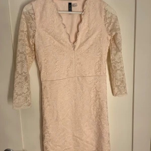 Ljusrosa spetsklänning från H&M - Säljer en söt ljusrosa klänning från hm  med v-ringning och trekvartsärmar. Klänningen är täckt av vacker spets och har en figurnära passform. Perfekt för vårens och sommarens fester! 🌸