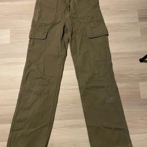 Gröna cargojeans  - Säljer ett par gröna cargojeabs med flera praktiska fickor. Byxorna har en loose passform och är perfekta för en avslappnad stil. De är tillverkade i ett slitstarkt material och har en klassisk design.