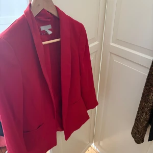 Röd kavaj - Finns att hämta på Kungsholmen. Snygg röd kavaj med klassisk design. Perfekt för att liva upp garderoben med en färgklick. Kavajen har en stilren passform och är ett mångsidigt plagg för olika tillfällen.