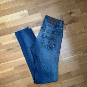 Blå jeans från T/J - Snygga blå jeans från T/J med en fransig kant vid bensluten, då jag valt att klippa de kortare. Jeansen är i storlek 26/34, men passar mig i längd som är 164cm. De har en klassisk femficksdesign. En bältesögla har gått upp. Perfekta för en avslappnad stil.