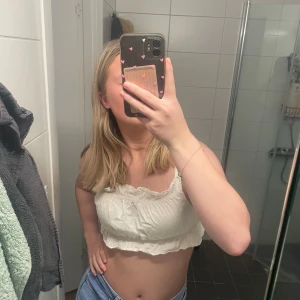 Vit croppad linnetopp - Säljer en söt vit croppad linnetopp med volangdetaljer. Perfekt för varma sommardagar. Toppen har justerbara axelband och en elastisk kant för en bekväm passform. Går att pruta 