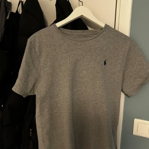 Grå t-shirt från Polo Ralph Lauren - Säljer en klassisk grå t-shirt från Polo Ralph Lauren med korta ärmar och rund hals. Den har en liten broderad logotyp på bröstet. 