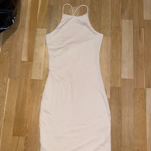Beige ribbad klänning från Gina Tricot - Snygg beige ribbad klänning från Gina Tricot i storlek XS. Klänningen har en tight passform med smala axelband och är perfekt för en stilren look.
