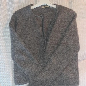 Grå kofta från Gina Tricot - Storlek: S. Nypris : 400kr.                          Säljer en stilren grå kofta från Gina Tricot i premiumkvalitet. Koftan har långa ärmar och knappar framtill, perfekt för kyliga dagar. Den är mjuk och bekväm att bära.