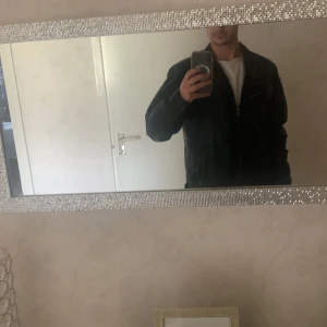 Svart skinnjacka från Rock'n Blue - Snygg svart skinnjacka från Rock'n Blue med flera dragkedjefickor och en stilren design. Jackan har en hög krage och långa ärmar, perfekt för en cool look. Dessutom är Jackan 100% äkta skinn. Orginalpriset är 3000 kr