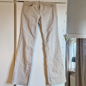 Beige bootcut jeans - Snygga beige byxor från H&M Divided i storlek 34. Byxorna har en klassisk femficksdesign och är tillverkade i ett bekvämt & mjukt material. Innerbenslängd: 80  midjemått: 35×2. Passar för dig som är 160 till 165cm lång🥰säljs för att dem är för små.