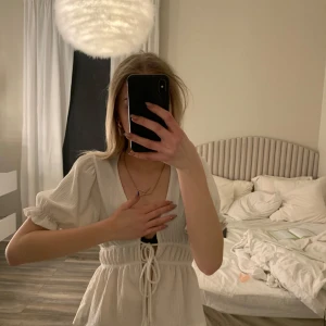 Vit blus med knytning - Säljer en söt vit blus med knytning framtill och korta ärmar. Perfekt för sommarens varma dagar. Blus har en v-ringad design och en luftig passform.