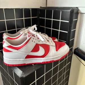 Nike Dunk i rött och vitt - Snygga Nike Dunk sneakers i en fräsch röd och vit färgkombination. Skorna har en klassisk design.