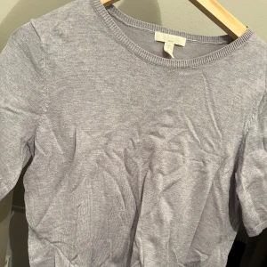 Grå tröja från H&M - Säljer en enkel och stilren grå tröja från H&M Basics. Tröjan har en rund halsringning och korta ärmar, perfekt för en avslappnad look. Passar bra till både jeans och kjol.