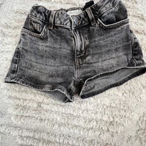 Svarta jeansshorts från Lindex - Snygga svarta jeansshorts från Lindex med en cool tvättad look. De har klassisk femficksdesign och en bekväm passform. Perfekta för en avslappnad stil.