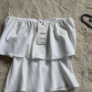 Vit bandeu/tubtop - Vit axelbandslös topp från Zara, endast testad med prislappen kvar! Säljs inte längre , ge prisförslag ☺️