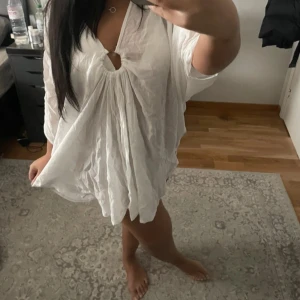 Vit cover up - V-ringad design och korta ärmar. Cover up för stranden. Aldrig använd ute.