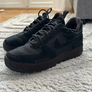 Snygga svarta Nike sneakers med en robust sula och klassisk snörning. Skorna har en kombination av mocka och syntetmaterial, vilket ger en stilren look. Perfekta för både vardag och träning. Använt dom MAX 5ggr