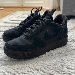 Svarta Nike sneakers - Snygga svarta Nike sneakers med en robust sula och klassisk snörning. Skorna har en kombination av mocka och syntetmaterial, vilket ger en stilren look. Perfekta för både vardag och träning. Använt dom MAX 5ggr