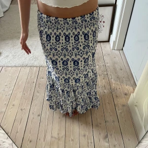 Vit och blå långkjol med mönster - Snygg långkjol i vitt och blått med ett unikt mönster, i fint skick 