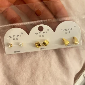 Set med örhängen från Weixi - Säljer ett set med tre par örhängen från Weixi. Setet innehåller ett par glittriga örhängen, ett par i guld med vriden design och ett par i guld med konform. Perfekt för att mixa och matcha till olika tillfällen.