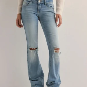 Ljusa jeans med slitningar - Snygga ljusblå jeans med slitningar på knäna. De har en klassisk femficksdesign och stängs med dragkedja och knapp. Perfekta för en avslappnad stil. Jag har klippt dom så dom passar mig som är ca 164