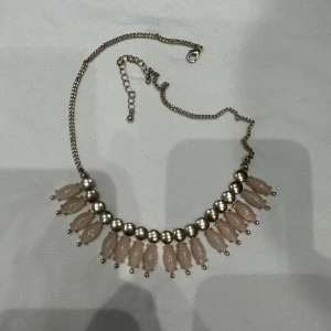 Halsband med pärldetaljer - Elegant halsband med silverkedja och dekorativa pärlor i ljusrosa nyans. Perfekt för att ge en stilfull touch till din outfit.